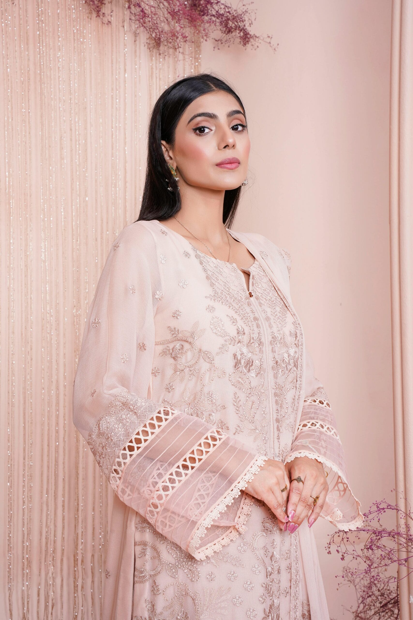 A stylish woman poses in an elegantly embroidered dress, showcasing fashion and beauty.