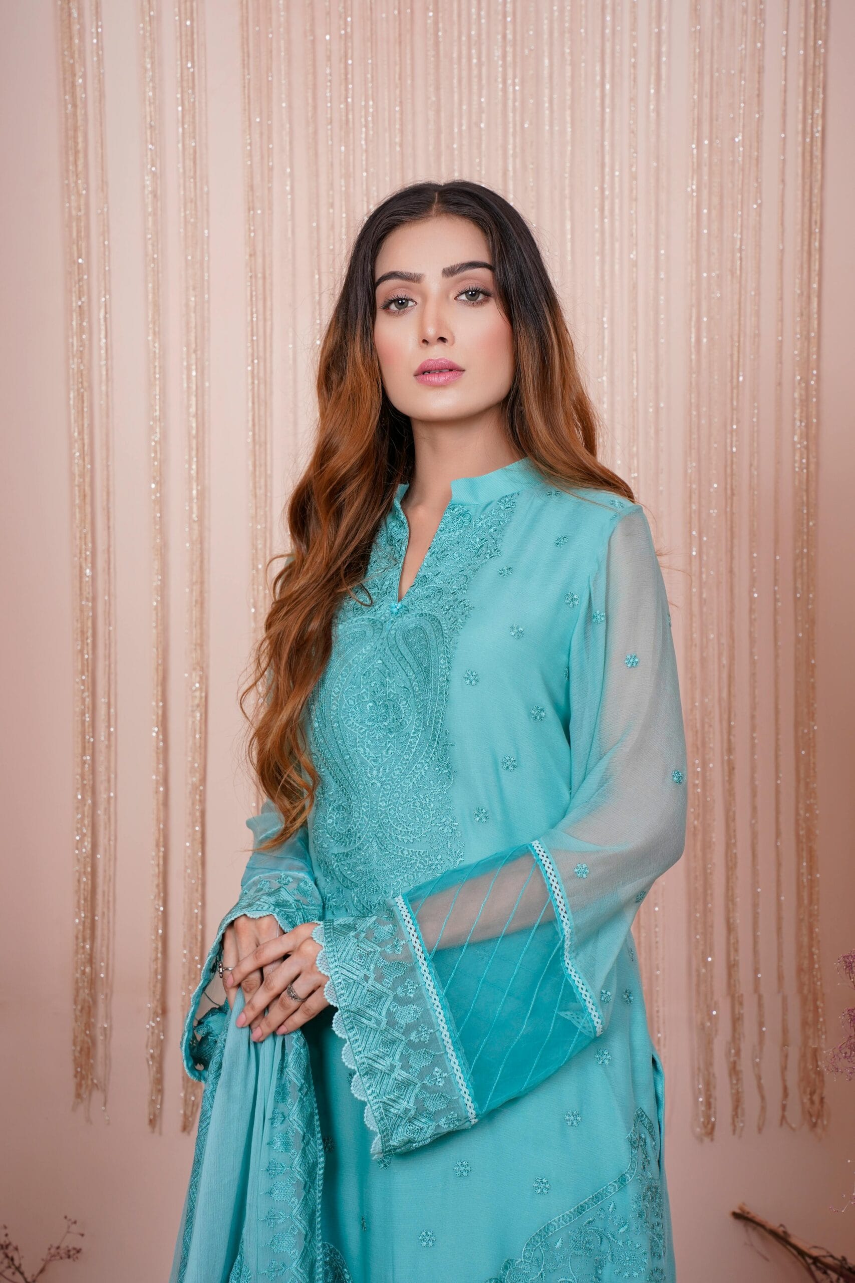 Beautiful portrait of a woman in a turquoise embroidered dress, showcasing fashion elegance.