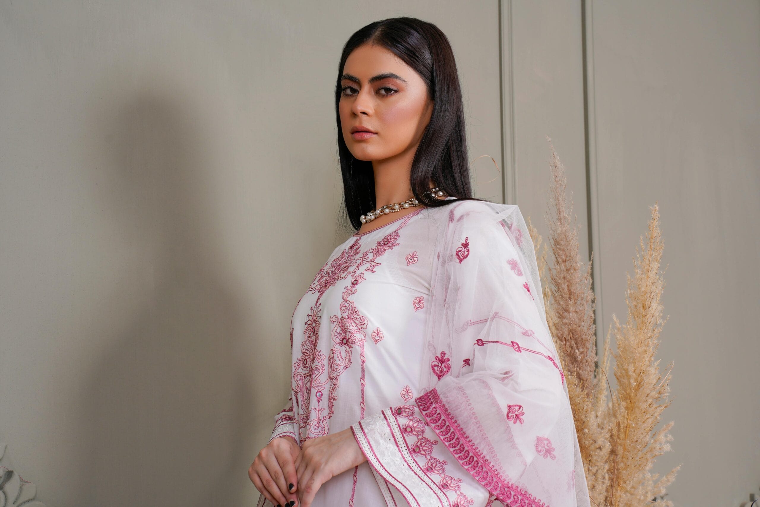 Stylish woman in an intricately embroidered dress posing indoors.