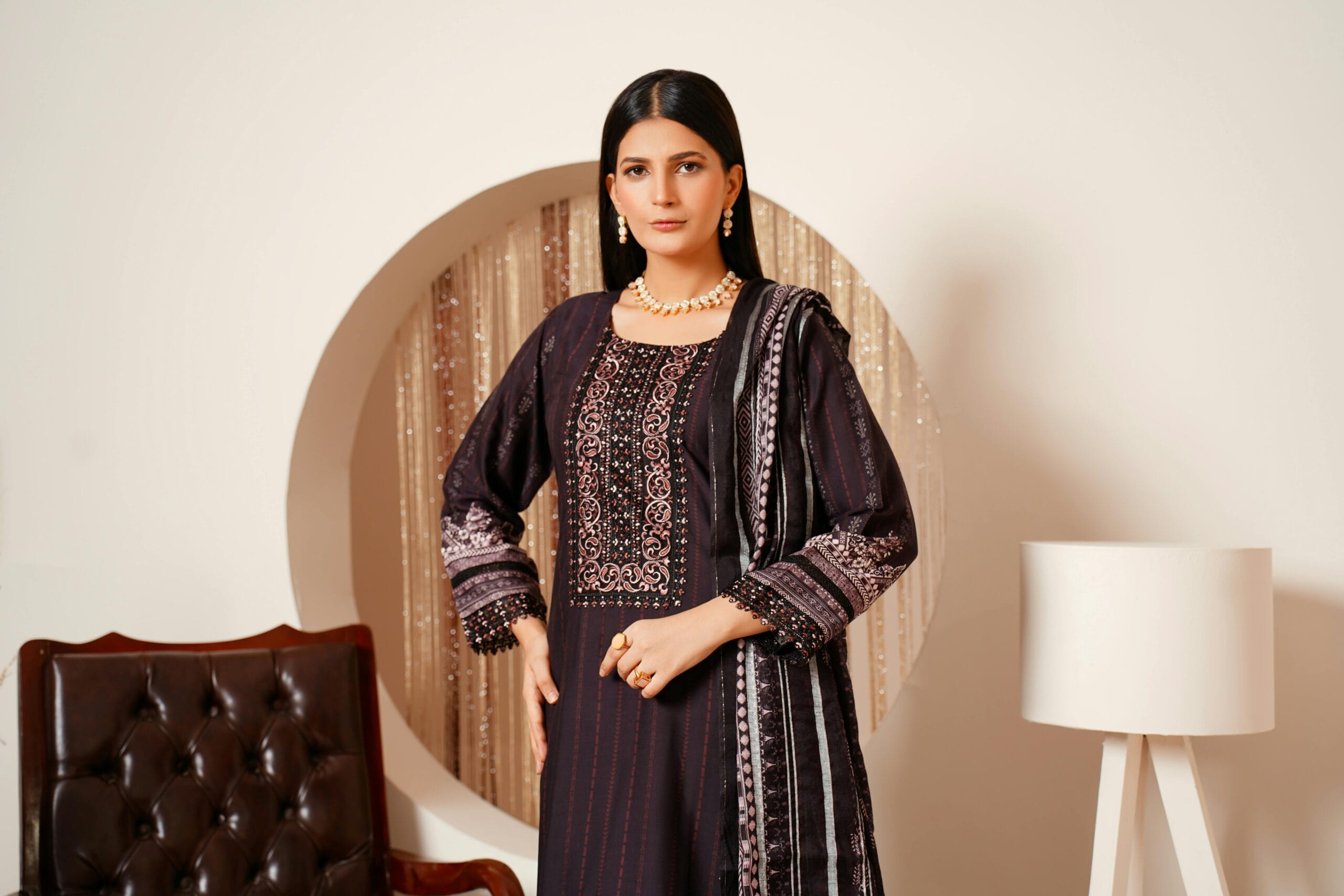 Portrait of a woman in a traditional Pakistani dress with elegant jewelry, indoors.